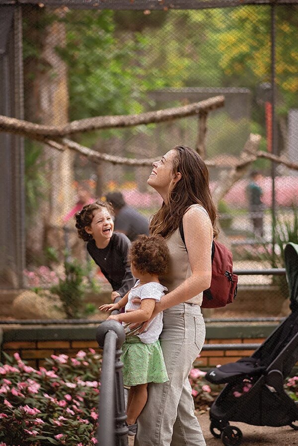 Mère avec deux enfants souriants observant un animal en captivité dans un cadre naturel