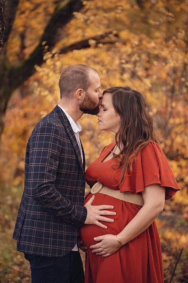 Couple attend un bébé en automne, homme embrassant le front d'une femme enceinte