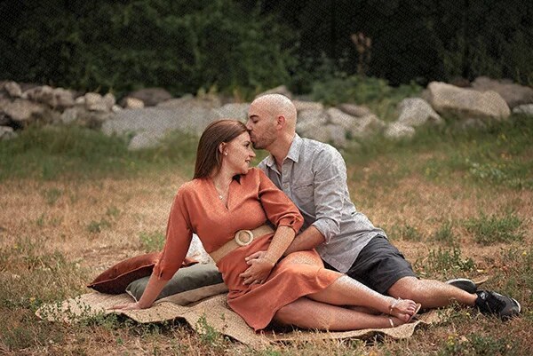 Couple assis sur une couverture en plein air, l'homme embrassant tendrement la femme sur le front
