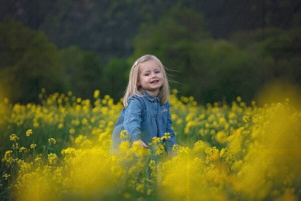 Petite fille souriante dans un champ de fleurs jaunes au crépuscule