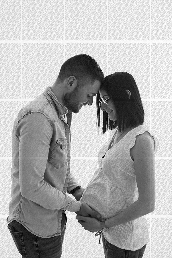 Couple souriant se tenant face à face, homme posant ses mains sur le ventre arrondi de la femme enceinte
