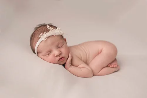 Nouveau-né endormi sur le côté avec un bandeau délicat, séance photo naissance paisible et douce